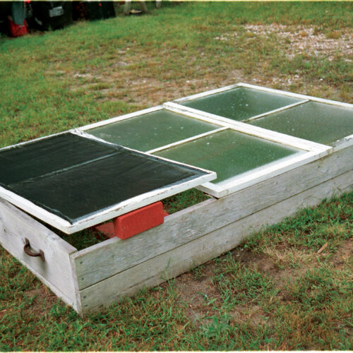 Soil blocks fit neatly into flats and cold frames. The flats are three-sided wooden frames that have an open side to allow for drainage (left). Flats filled with mature seedlings are placed in a cold frame for hardening off (right).